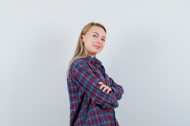 Signora bionda in camicia casual in piedi con le braccia incrociate e guardando fiducioso, vista frontale.