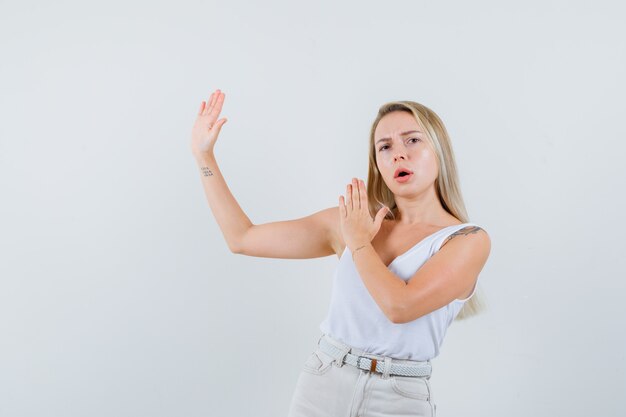 Signora bionda in canottiera, pantaloni che mostrano il gesto del colpo di karate e che sembra sicura