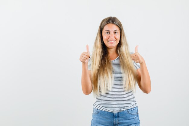 Signora bionda in maglietta che mostra pollice in su e che sembra felice, vista frontale.