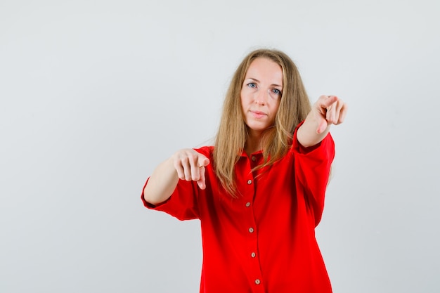 Signora che indica alla macchina fotografica in camicia rossa e che sembra sicura,