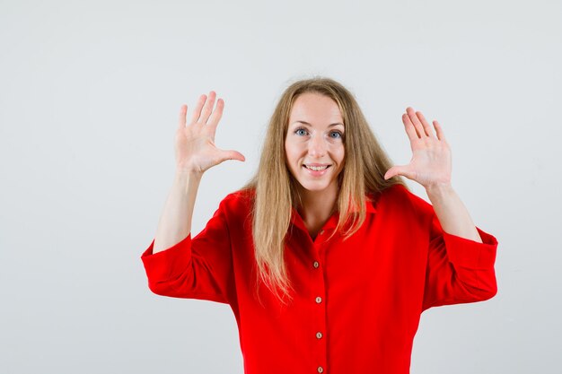 Signora che mostra dieci dita in camicia rossa e sembra allegra.