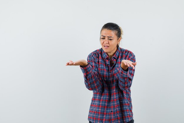 Signora che solleva le mani in gesto perplesso in vista frontale camicia casual.