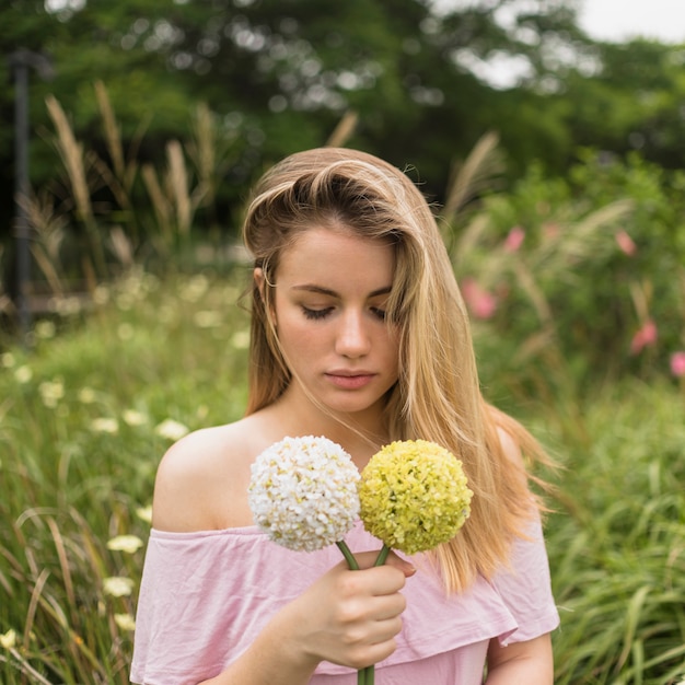 Signora che tiene i fiori luminosi nel parco