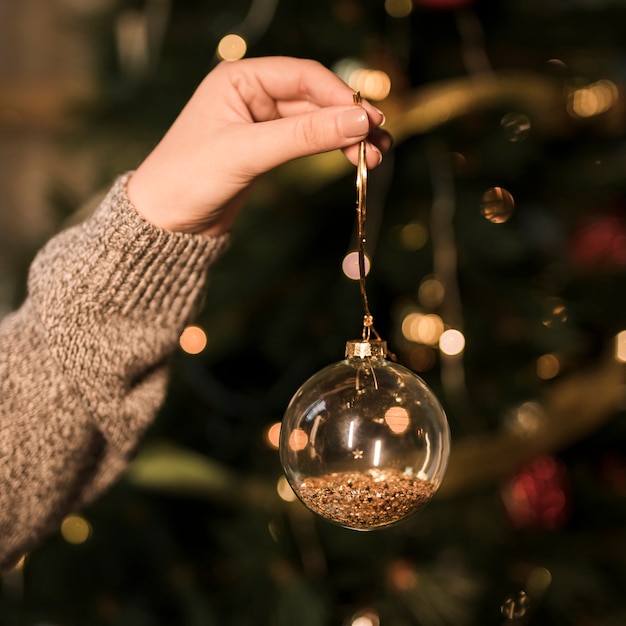 Signora che tiene ornamento trasparente palla di Natale