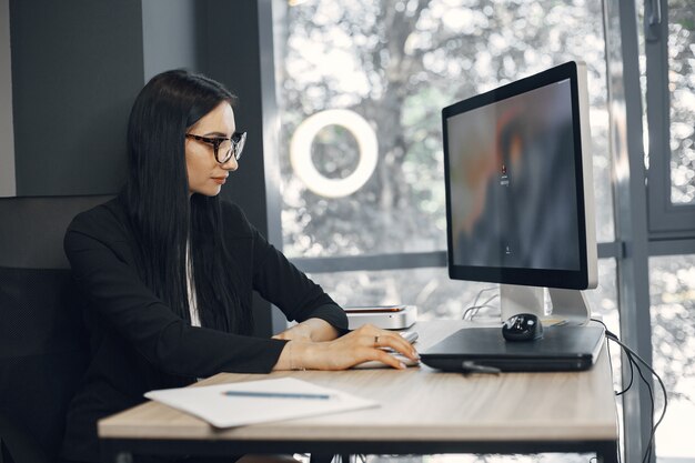 Signora con gli occhiali. Il manager è seduto al computer. La donna di affari lavora nel suo ufficio.