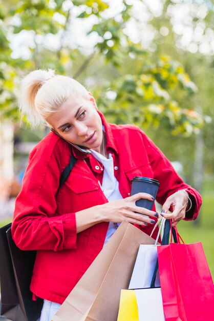 Signora con pacchetti di acquisto che parlano di smartphone