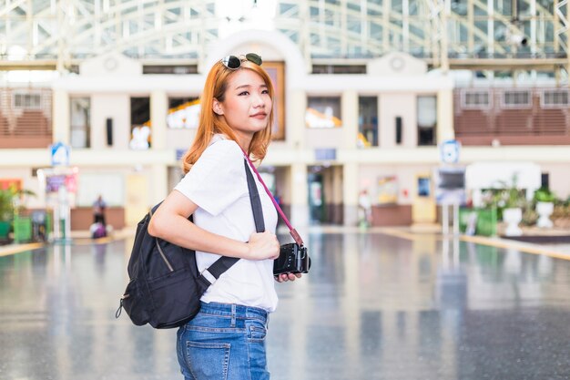 Signora con zaino e macchina fotografica sulla stazione ferroviaria