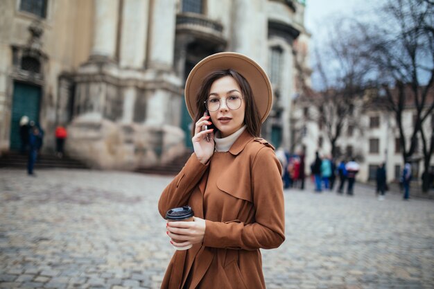 Signora dai capelli corti che parla sul telefono e sui messaggi di testo sul suo telefono