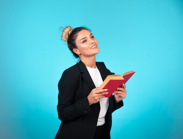 Signora di affari in giacca sportiva nera con un pensiero del libro rosso.