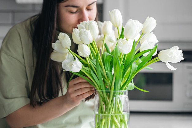 Signora di casa che si gode un bouquet di fiori nell'interno della cucina