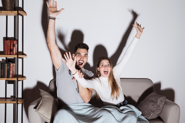 Signora e tipo sorridenti che guardano TV sul sofà