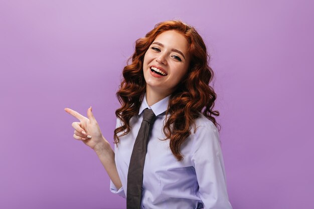 Signora in camicia blu che indica il posto per il testo sul muro viola