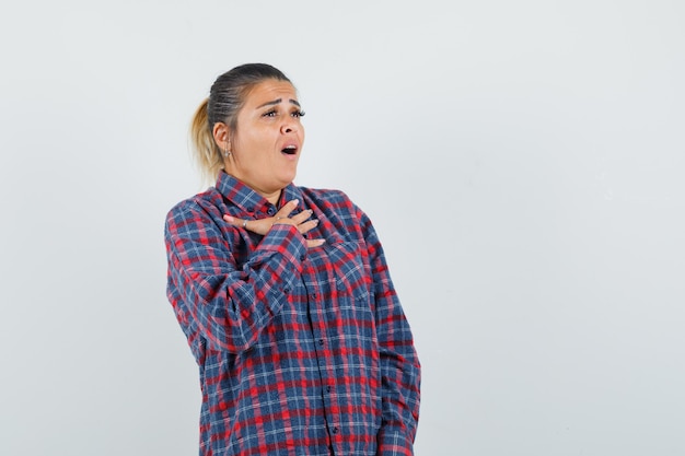 Signora in camicia casual che tiene la mano sul petto e che sembra eccitata, vista frontale.