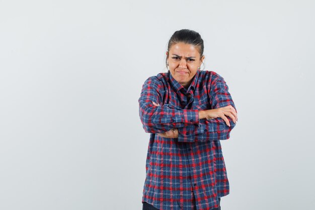 Signora in camicia casual in piedi con le braccia incrociate e guardando dispettoso, vista frontale.