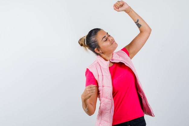 Signora in t-shirt, gilet che mostra il gesto del vincitore e sembra felice