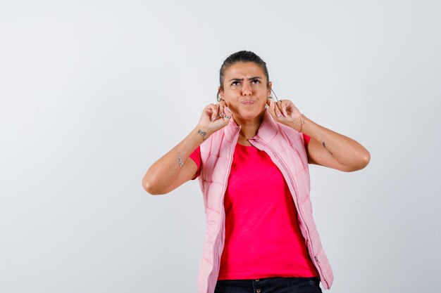 Signora in t-shirt, gilet che tiene le dita sul collo e sembra cupa