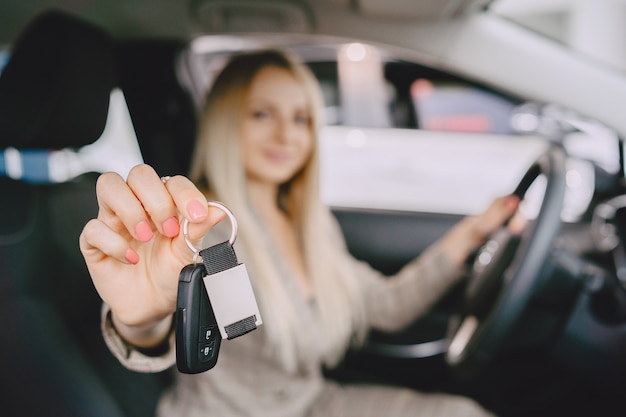 Signora in un salone di automobile. Donna che compra l'auto. Donna elegante in un abito marrone.