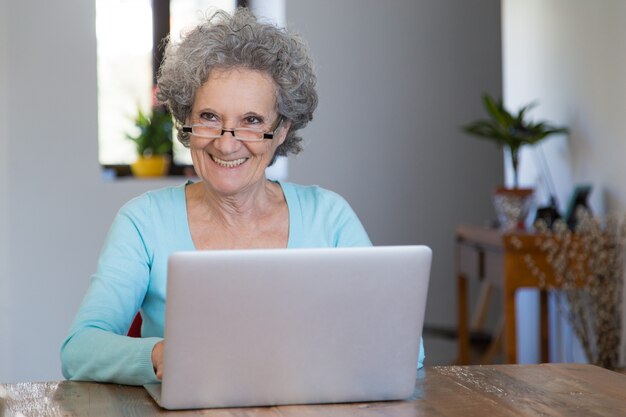 Signora senior allegra che utilizza i servizi online