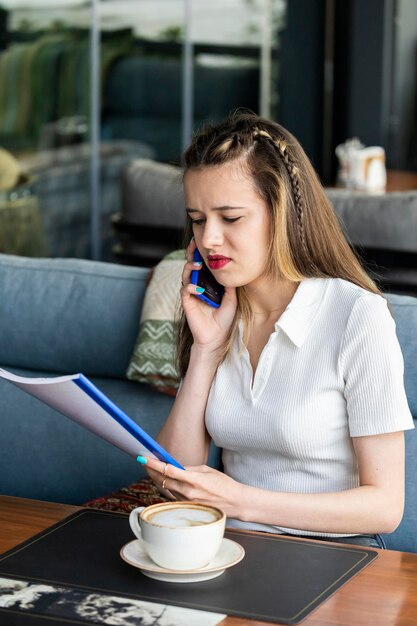 Signora seria che parla al telefono e che esamina il taccuino