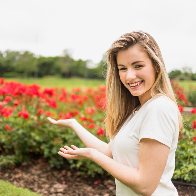 Signora sorridente in maglietta vicino a fioriture rosse