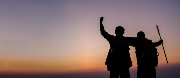 Silhouette di coppia escursionistica tifosa a braccia aperte verso l'alba in montagna con spazio per la copia Viaggio Lifestyle Wanderlust concetto di avventura vacanze estive all'aperto