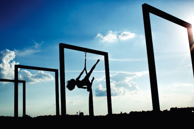 Silhouette di danza aerea di seta sul tetto al tramonto