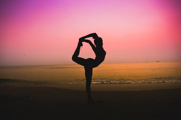 Silhouette di donna che fa yoga su una spiaggia