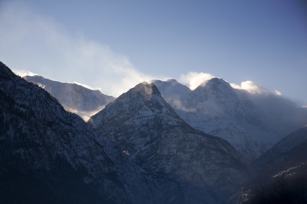 Silhouette di montagne rocciose ricoperte di neve e nebbia durante l'inverno