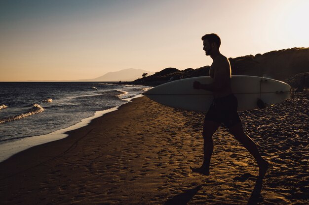 Silhouette di surfista a piedi verso il mare