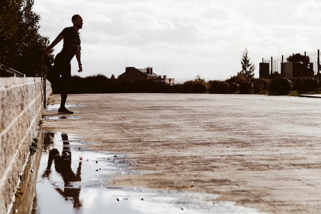 Silhouette di un uomo che si estende vicino alla pozza d&#39;acqua