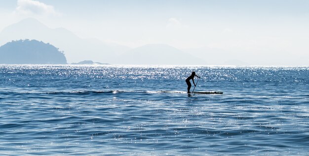 Silhouette di una donna stand up paddle surf al mare in Brasile