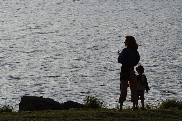 Silhouette di una madre e suo figlio contro una laguna al tramonto