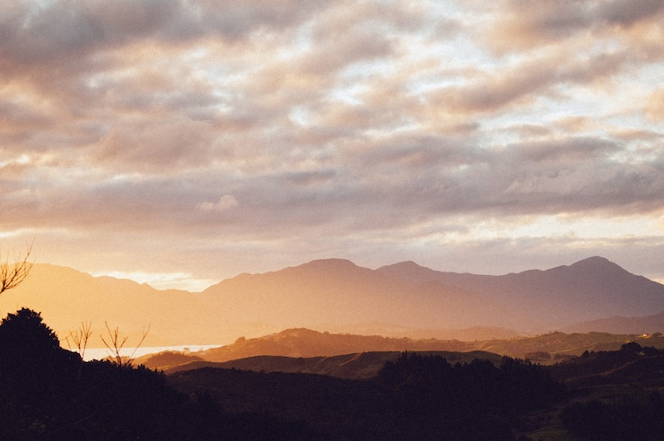 Foto gratuito silhouette di una serie di bellissime montagne sotto il cielo al tramonto mozzafiato
