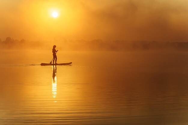 Silhouette di uomo attivo in piedi sul paddle board