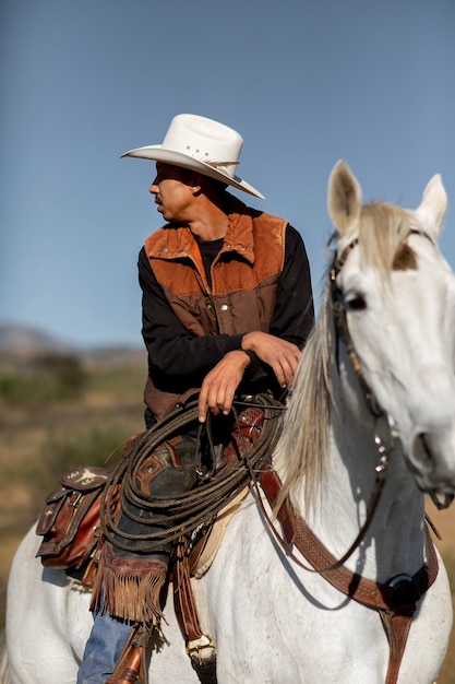 Siluetta del cowboy con il cavallo contro la luce calda