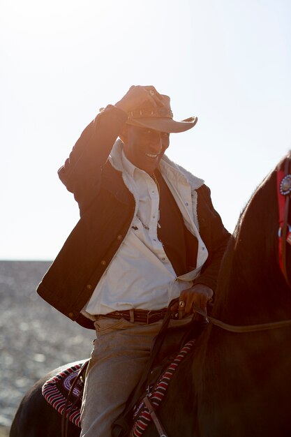 Siluetta del cowboy con il cavallo contro la luce calda