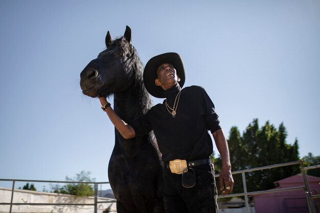Siluetta del cowboy con il cavallo contro la luce calda