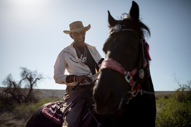 Siluetta del cowboy con il cavallo contro la luce calda