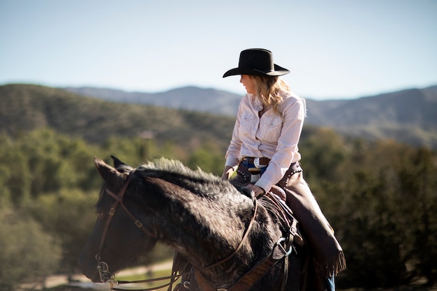 Siluetta del cowboy con il cavallo contro la luce calda