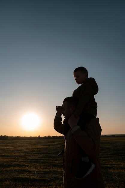 Siluetta della famiglia del colpo medio che si diverte al tramonto