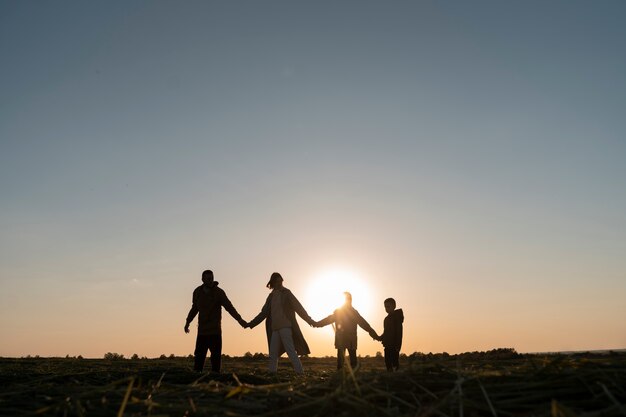 Siluetta della famiglia del colpo pieno che si diverte al tramonto