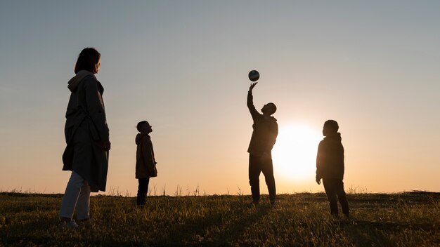 Siluetta della famiglia del colpo pieno che si diverte al tramonto