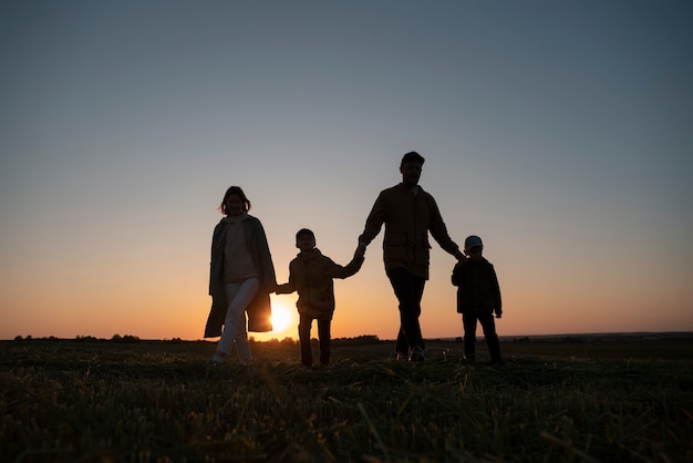 Siluetta della famiglia del colpo pieno che si diverte al tramonto