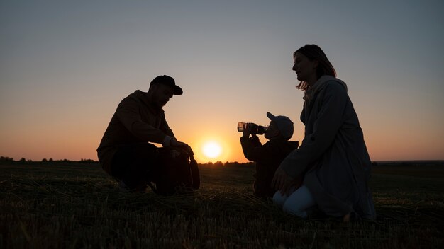 Siluetta della famiglia del colpo pieno che si diverte al tramonto