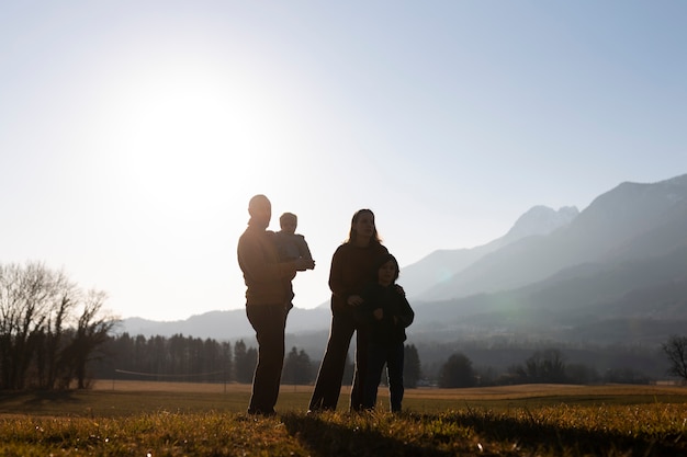 Siluetta della famiglia del colpo pieno in natura al tramonto