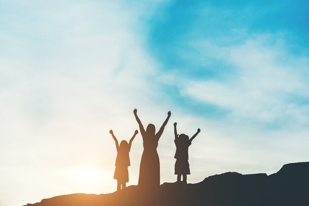 Siluetta della madre con sua figlia in piedi e tramonto