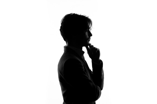 Siluetta della persona di sesso maschile in vestito rigoroso pensando vista laterale ombra retroilluminato sfondo bianco
