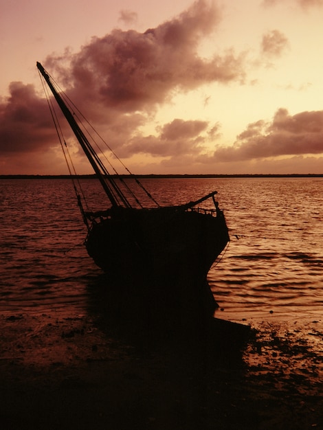 Siluetta di una barca su una riva vicino all'acqua sotto un cielo rosa a Lamu, Kenya