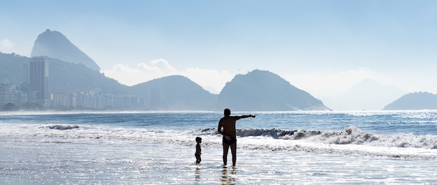 Siluette del padre e del bambino che giocano sulla riva del mare in Brasile