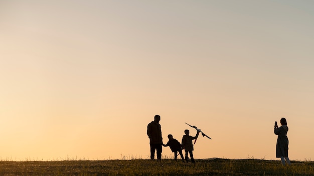 Siluette della famiglia che si divertono al tramonto a tutto campo